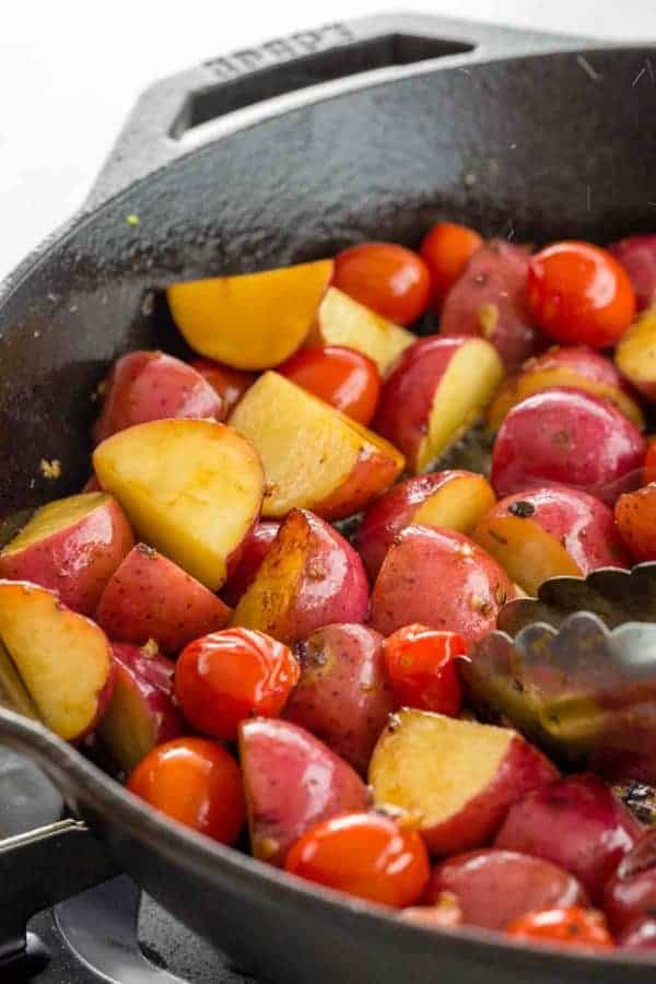 土豆和烹调在铸铁平底锅的婴孩蕃茄照片