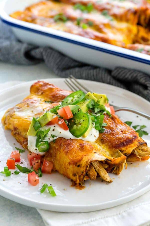 鸡Enchiladas板材冠上用酸奶油，鳄梨和墨西哥胡椒