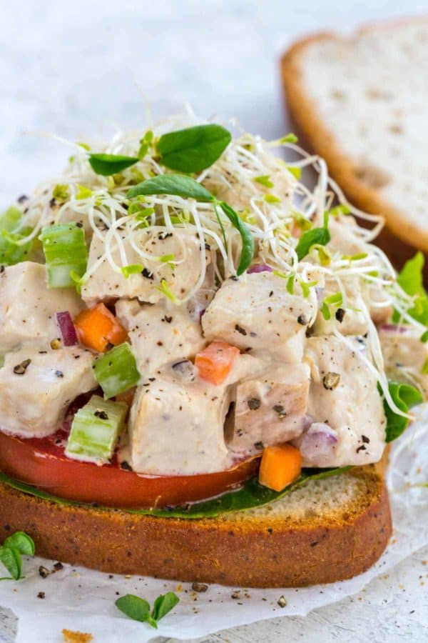 Open faced chicken salad sandwich topped with sprouts