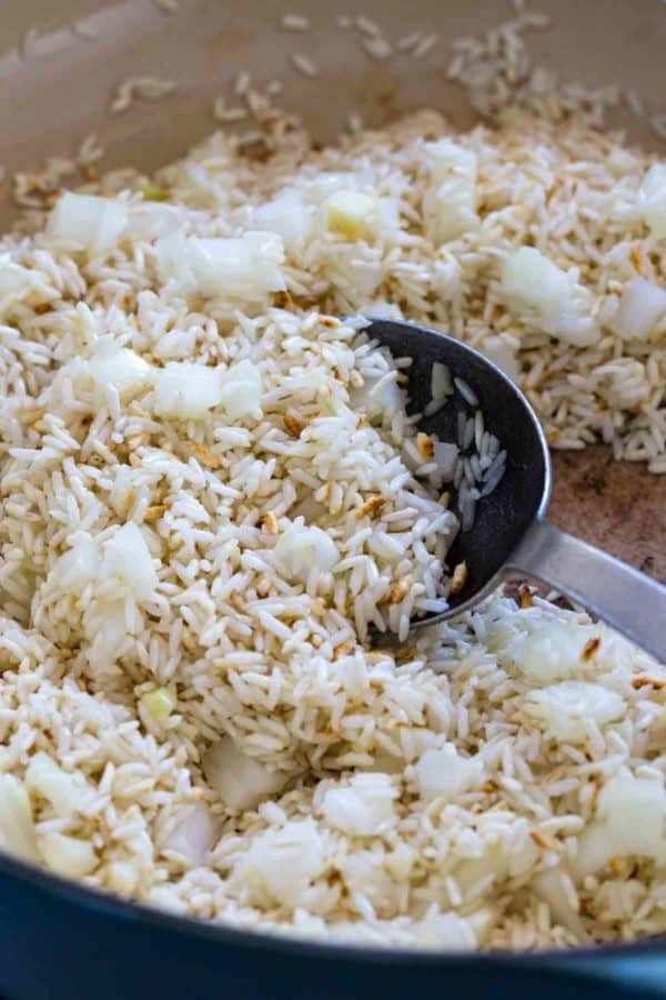 勺子混合水稻和洋葱在锅内