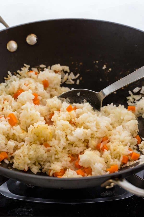 勺子混合米饭和胡萝卜在炒锅里