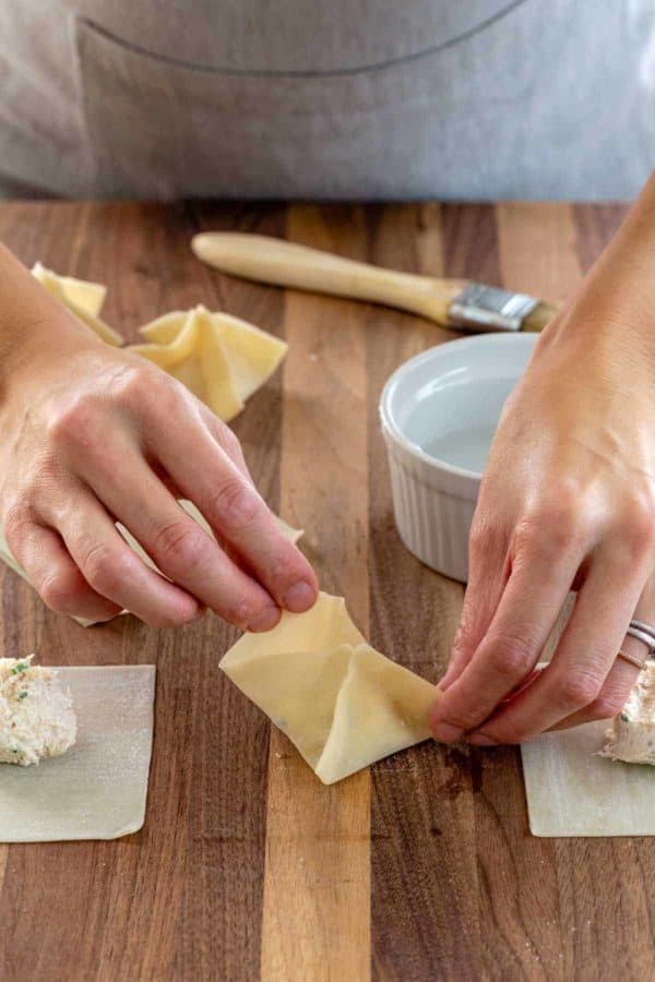 Person folding wonton wrapper into a purse shape.