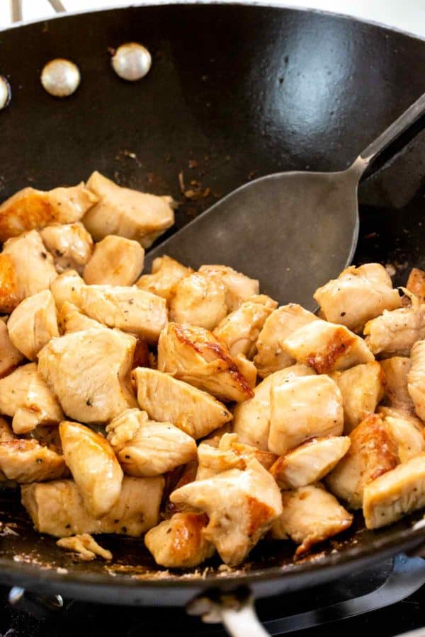 用刮刀在锅里移动小块白肉鸡肉