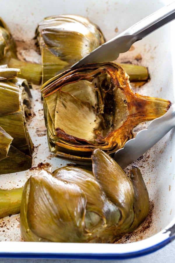 金属钳子在烤盘里翻动烤洋蓟