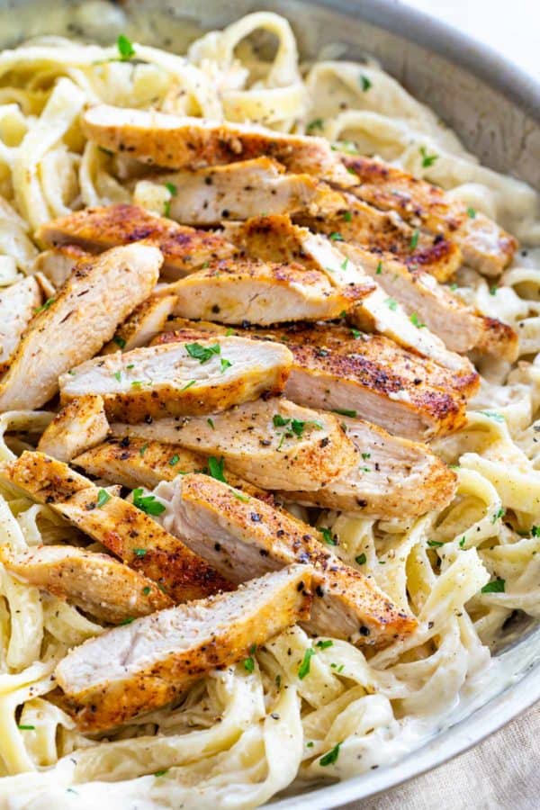 slices of chicken served on top of fettuccine and alfredo sauce