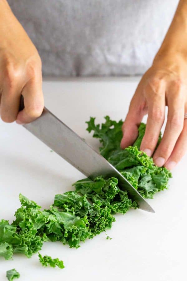 chopping kale on a butting board with a chefs knife