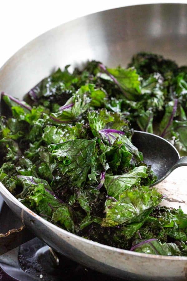 cooking sauteed kale in a metal skillet