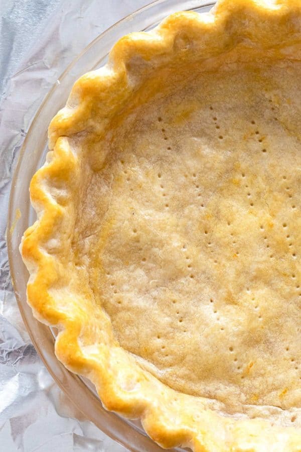 partially cooked pie crust in a glass plate