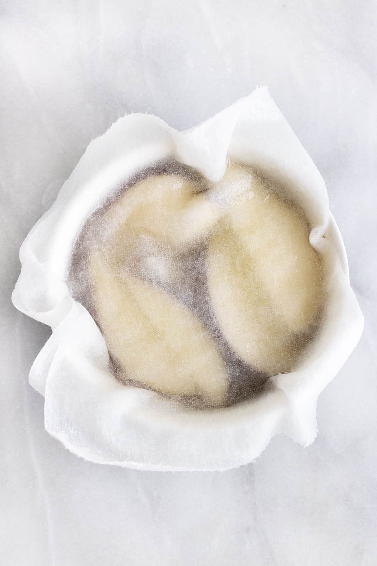 Sliced apples in water with a paper towel placed on top of the bowl.