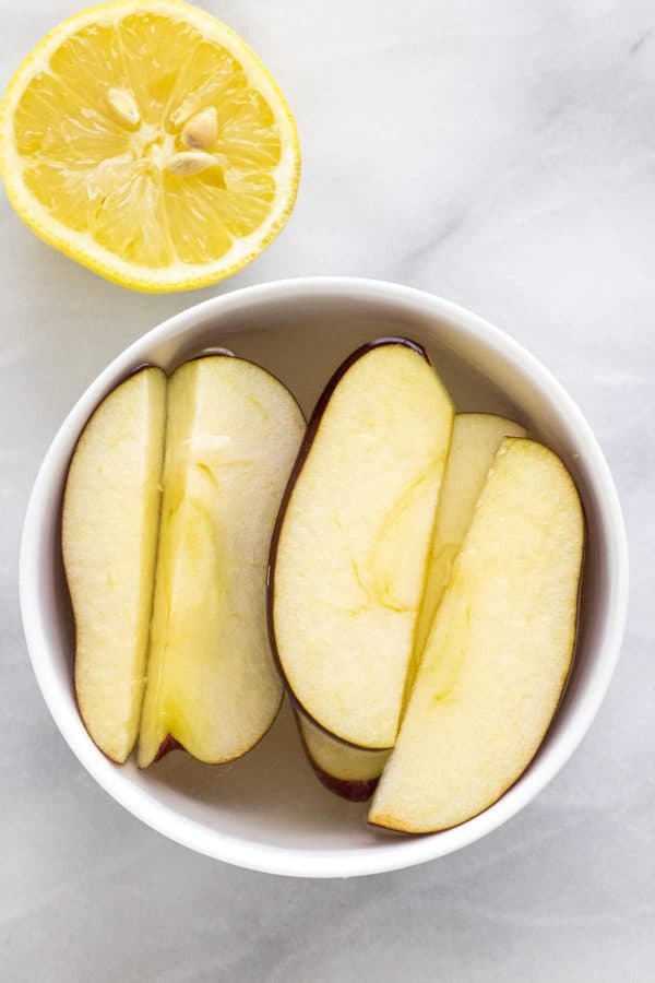 Apple slices in a bowl of lemon juice and water mixture.