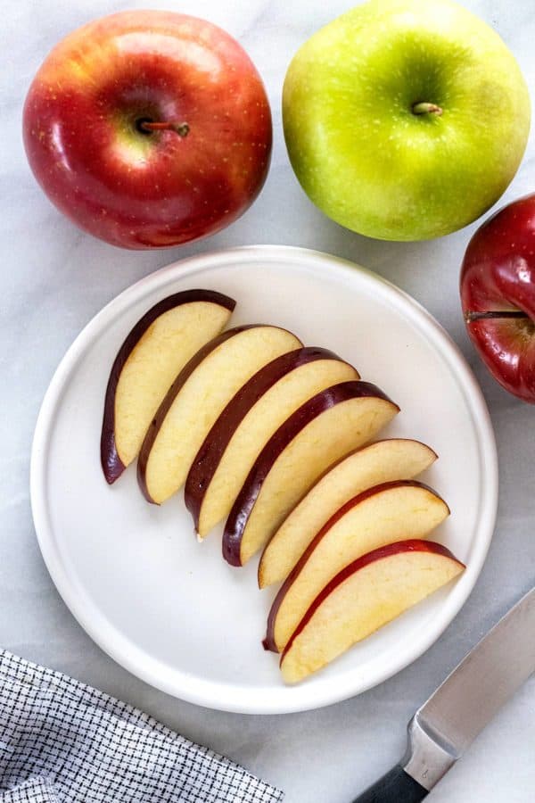 Slices of red apple on a plate showing the white colored flesh.