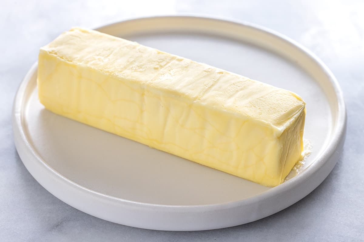 A stick of margarine on a white plate.